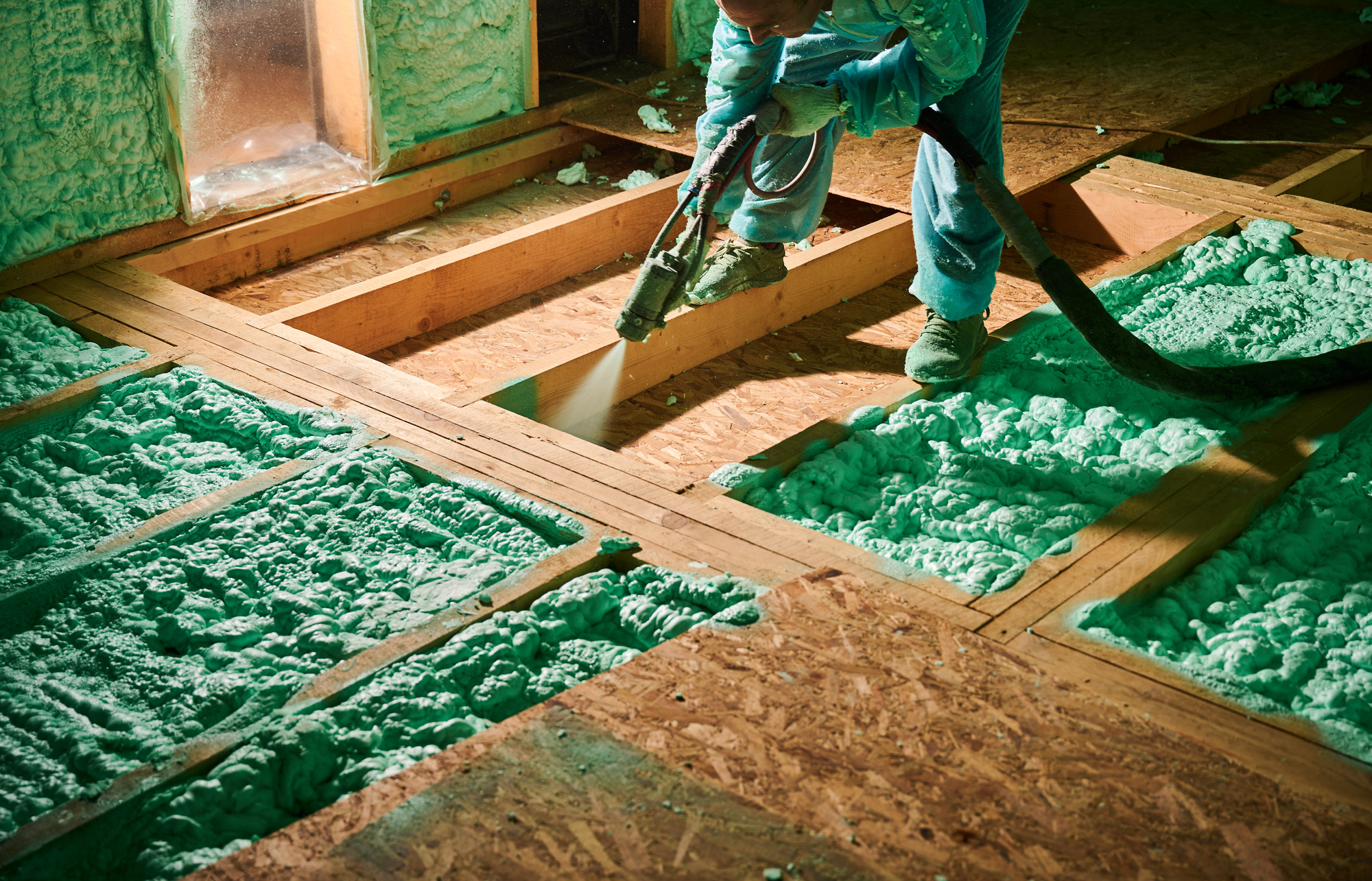 An expert from CT Insulation Services installing spray foam insulation above the ceiling in a home